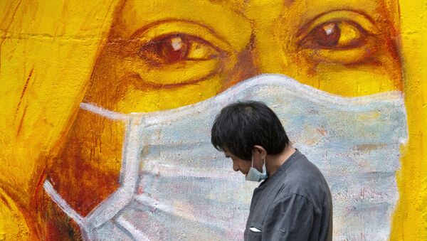 Прохожий около стены с изображением человека в маске в Гонконге - Sputnik Южная Осетия