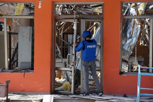 Представитель СМИ возле здания магазина в Мартакерте, разрушенного в результате обстрелов - Sputnik Южная Осетия