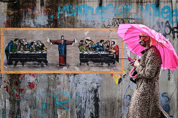 Женщина в леопардовой защитной маске на фоне граффити итальянского художника TvBoy в Милане, Италия - Sputnik Южная Осетия