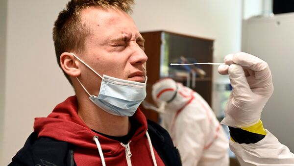Медицинский работник берет образец мазка у человека на участке тестирования COVID-19 в Оравски-Подзамок, Словакия - Sputnik Южная Осетия