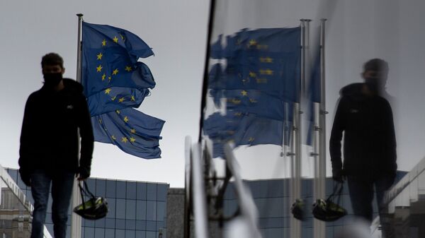 Мужчина идет мимо флагов ЕС у штаб-квартиры ЕС в Брюсселе - Sputnik Южная Осетия