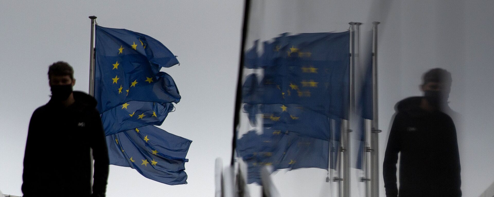 Мужчина идет мимо флагов ЕС у штаб-квартиры ЕС в Брюсселе - Sputnik Южная Осетия, 1920, 31.01.2022