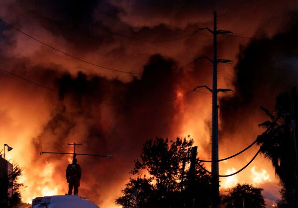 Пожарный стоит на резервуаре с водой во время пожара на заводе по переработке металлолома компании Deacero в Гуадалупе, на окраине Монтеррея, Мексика - Sputnik Южная Осетия