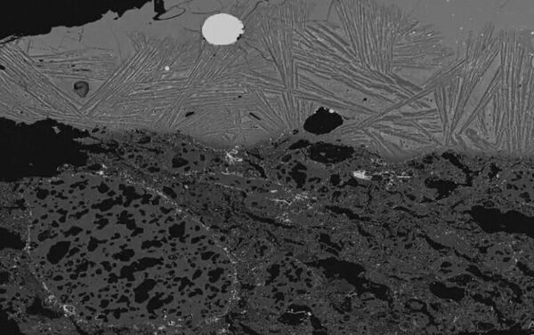 Изображение шлака внутри тигля, полученное с помощью сканирующего электронного микроскопа, с серебристым стальным пятном, видимым в центре вверху - Sputnik Южная Осетия