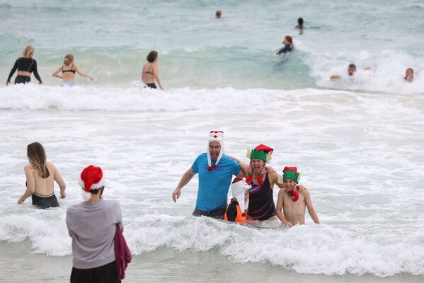 Люди в рождественской одежде позируют для фотографий в Рождество на пляже Бонди в Сиднее, Австралия - Sputnik Южная Осетия
