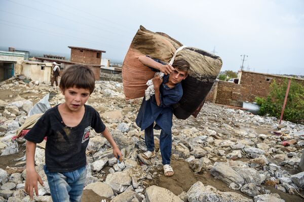 Молодые люди спасают остатки вещей из развалин домов после внезапного наводнения в Чарикаре, провинция Парван, Афганистан - Sputnik Южная Осетия