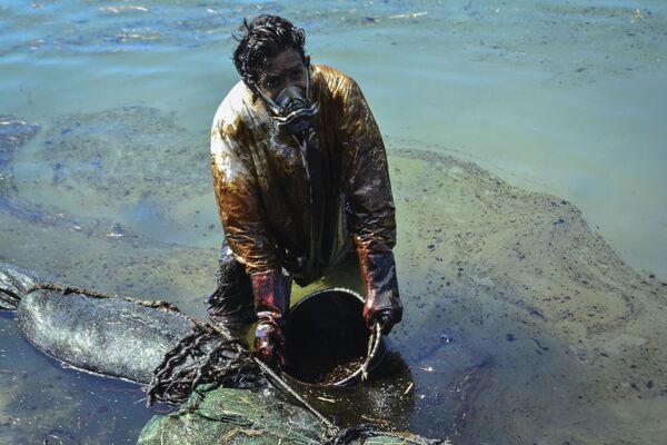 Мужчина очищает воду от разлившейся у берегов Маврикия нефти. - Sputnik Южная Осетия