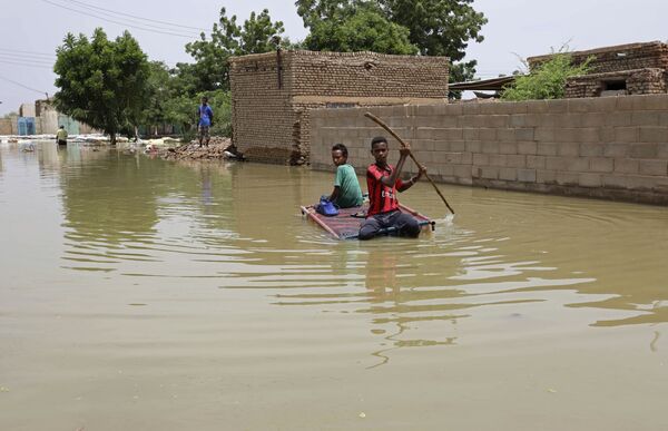 Подростки плывут на плоту по затопленной в результате наводнения улице в городе Салмания, Судан - Sputnik Южная Осетия