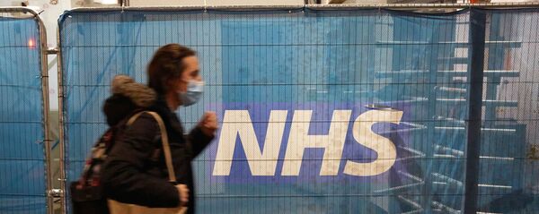 Девушка возле баннера Национальной службы здравоохранения Великобритании - Sputnik Южная Осетия