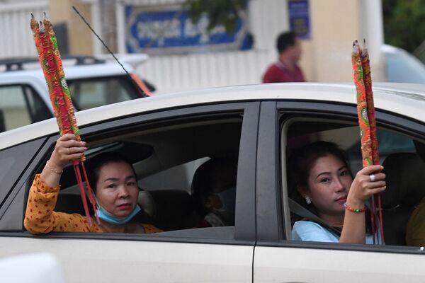 Женщины с ароматическими палочками в машине во время празднования Нового года по лунному календарю в Такмау, Камбоджа - Sputnik Южная Осетия