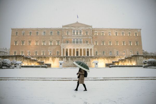 Женщина с зонтиком проходит мимо здания парламента во время сильного снегопада в Афинах, Греция - Sputnik Южная Осетия