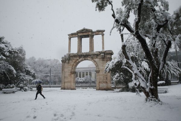 Пешеход идет рядом с воротами Адриана во время сильного снегопада в Афинах, Греция - Sputnik Южная Осетия