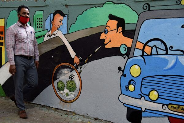 Пешеход идет мимо стены с граффити на тему коронавируса в Мумбае, Индия - Sputnik Южная Осетия