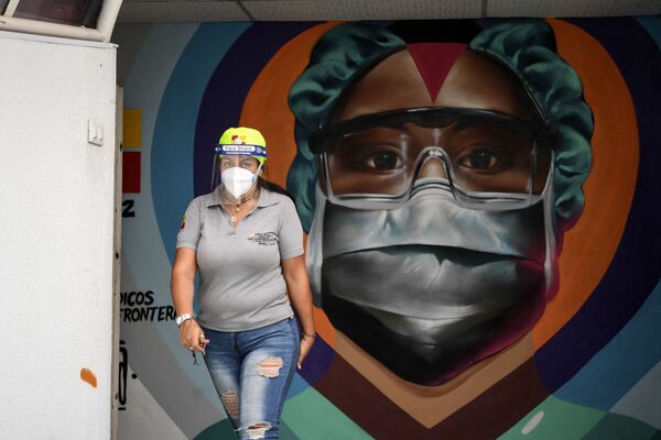 Медицинский работник в защитной маске у граффити в Каракасе - Sputnik Южная Осетия