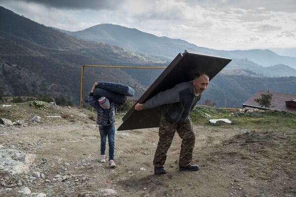 Мурад Мвргарян и его сын Ваак выносят вещи из своего дома перед тем, как покинуть город Лачин - Sputnik Южная Осетия