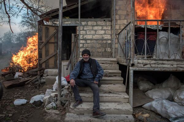 Местный житель Арег сидит у горящего дома в поселке Карегах, Нагорный Карабах. Некоторые жители сожгли свои дома перед тем как уйти - Sputnik Южная Осетия