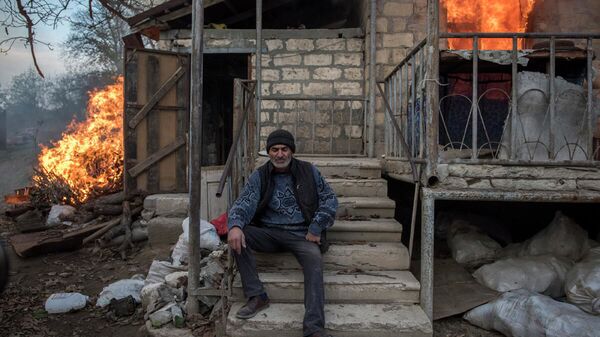 Местный житель Арег сидит у горящего дома в поселке Карегах, Нагорный Карабах. Некоторые жители сожгли свои дома перед тем как уйти - Sputnik Южная Осетия