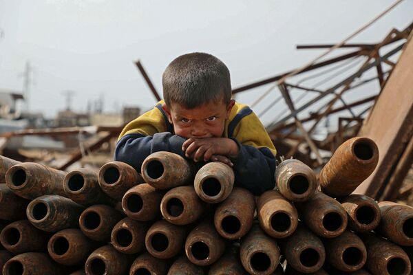 Ребенок на куче нейтрализованных снарядов на свалке металлолома города Маарет-Мисрин в  провинции Идлиб, Сирия - Sputnik Южная Осетия