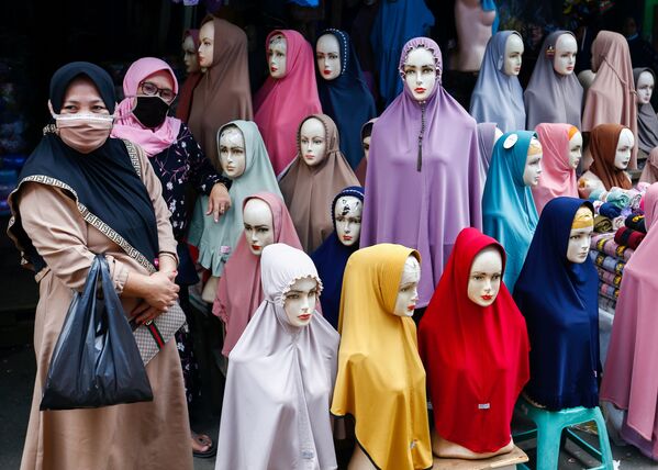 Женщины в защитных масках стоят рядом с хиджабами, выставленными на продажу на текстильном рынке Танах Абанг в Джакарте, Индонезия - Sputnik Южная Осетия