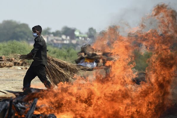 Рабочий проходит мимо горящего погребального костра человека, умершего из-за коронавируса Covid-19, Индия  - Sputnik Южная Осетия