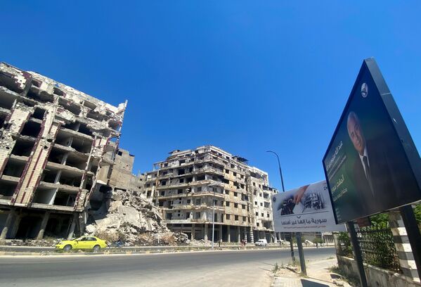 Рекламный щит предвыборной кампании кандидата в президенты Абдаллы Салума Абдаллаха возле поврежденных зданий в Хомсе - Sputnik Южная Осетия