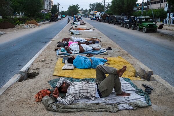 Рабочие спят на разделительной полосе на улице портового города Карачи, Пакистан - Sputnik Южная Осетия