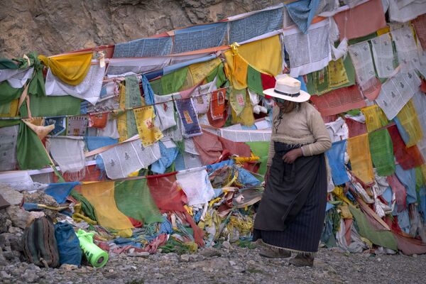Женщина проходит мимо молитвенных флагов у буддийского храма в Намцо, Тибет - Sputnik Южная Осетия