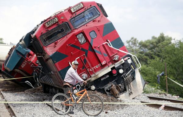 Мужчина с велосипедом проезжает мимо поезда, который сошел с рельсов в районе Сан-Исидро-Масатепек в Тала, штат Халиско, Мексика - Sputnik Южная Осетия