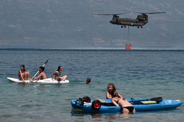 Отдыхающие во время забора воды вертолетом для тушения природных пожаров в Греции  - Sputnik Южная Осетия