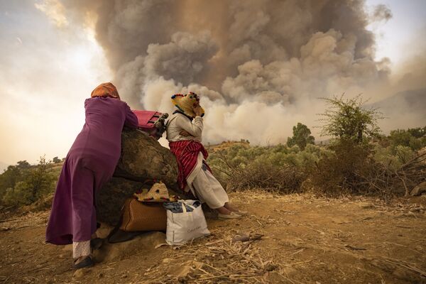Женщины на горной дороге со своими вещами во время лесных пожаров на севере Марокко  - Sputnik Южная Осетия