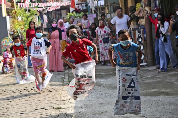 Дети в масках принимают участие в соревнованиях по бегу в мешках во время празднования Дня независимости в Джакарте, Индонезия - Sputnik Южная Осетия