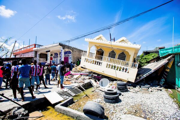 Люди стоят рядом с домом, разрушенным в результате землетрясения силой 7,2 балла в Ле-Ке, Гаити - Sputnik Южная Осетия