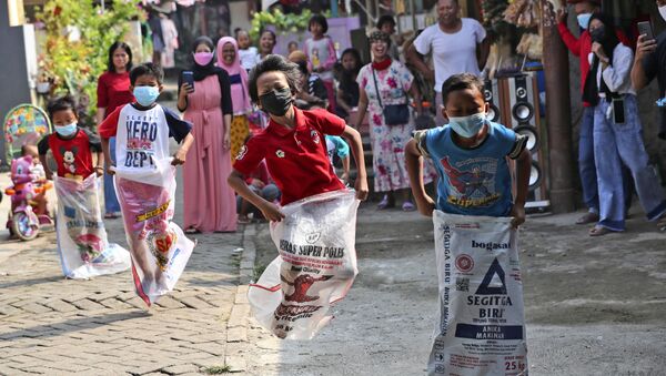 Дети в масках принимают участие в соревнованиях по бегу на мешках во время празднования Дня независимости в Джакарте, Индонезия - Sputnik Южная Осетия
