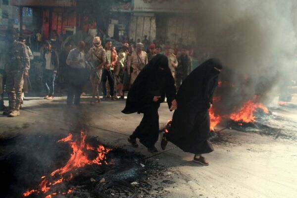 Женщины пробегают мимо горящих покрышек во время протестов против ухудшения экономической ситуации и девальвации местной валюты в Таизе, Йемен - Sputnik Южная Осетия