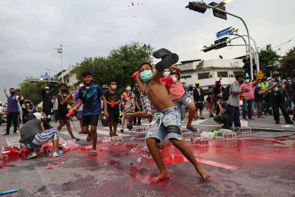 Молодые антиправительственные протестующие бросают бутылки с красной краской в ​​полицию во время демонстрации в Бангкоке - Sputnik Южная Осетия