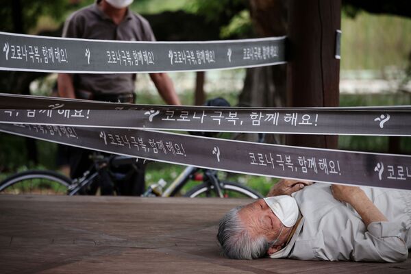 Мужчина отдыхает у павильона, который был оцеплен в качестве меры по предотвращению распространения COVID-19 в парке Сеуле, Южная Корея - Sputnik Южная Осетия