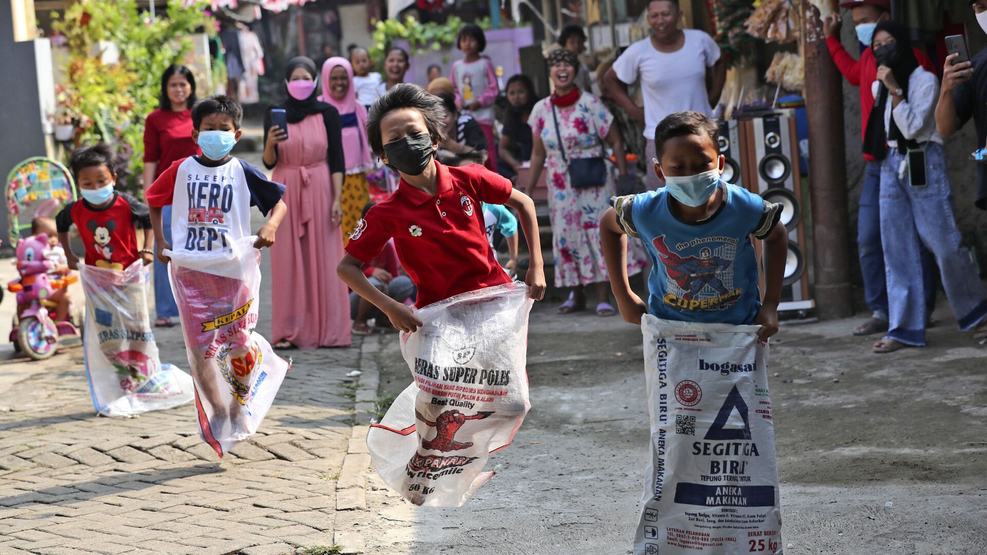 Дети в масках принимают участие в соревнованиях по бегу на мешках во время празднования Дня независимости в Джакарте, Индонезия - Sputnik Южная Осетия, 1920, 27.11.2021