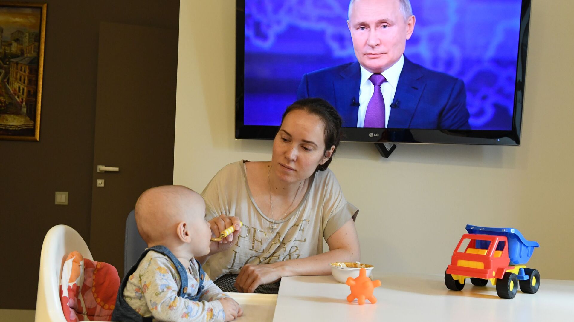 Женщина с ребенком смотрят трансляцию прямой линии с президентом России Владимиром Путиным - Sputnik Южная Осетия, 1920, 29.01.2022