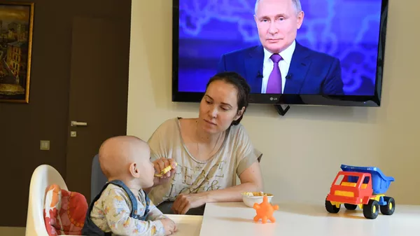 Женщина с ребенком смотрят трансляцию прямой линии с президентом России Владимиром Путиным - Sputnik Южная Осетия