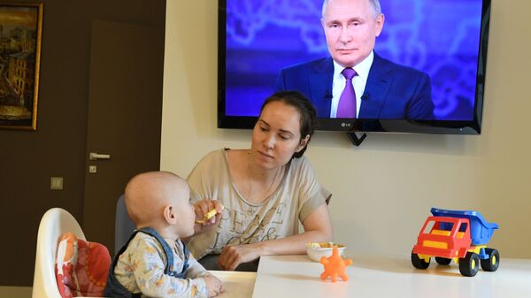 Женщина с ребенком смотрят трансляцию прямой линии с президентом России Владимиром Путиным - Sputnik Южная Осетия