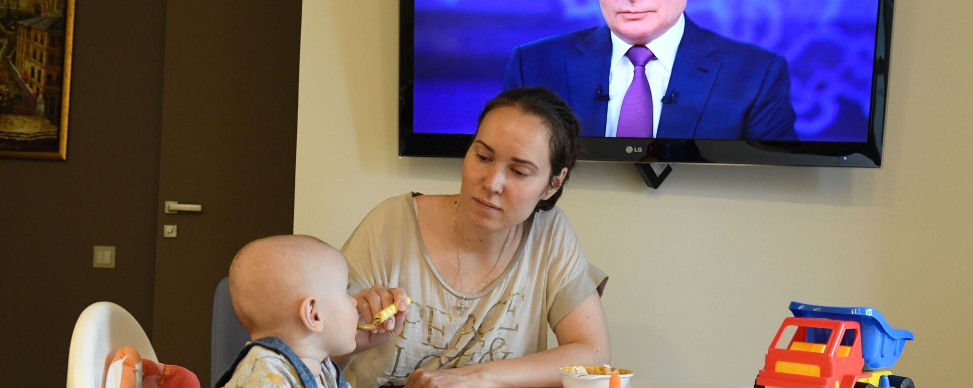 Женщина с ребенком смотрят трансляцию прямой линии с президентом России Владимиром Путиным - Sputnik Южная Осетия, 1920, 11.12.2021