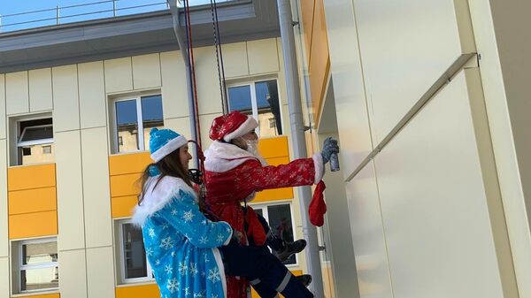 Дед Мороз и Снегурочка спустились с крыши к пациентам РДКБ и подарили через окна подарки - Sputnik Южная Осетия