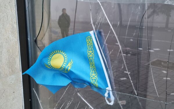 Государственный флаг Казахстана виден в разбитом окне отделения Kaspi Bank после протестов, вызванных повышением цен на топливо в Алматы - Sputnik Южная Осетия