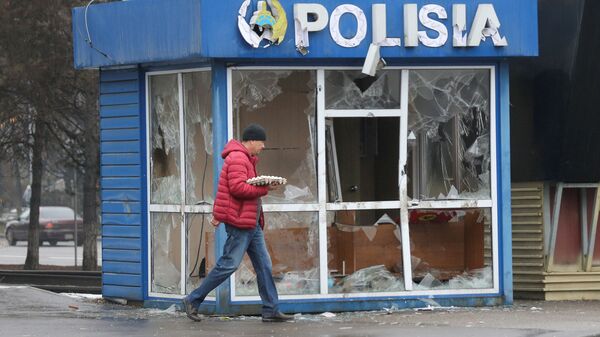 Мужчина проходит мимо полицейского участка, разрушенного во время беспорядков в Алматы - Sputnik Южная Осетия