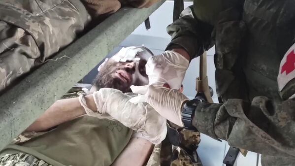 Медик оказывает помощь одному из раненых украинских военных с Азовстали в Мариуполе - Sputnik Южная Осетия