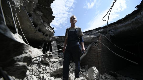 Мужчина на месте попадания снаряда ВСУ в крышу Донецкого центра охраны материнства и детства - Sputnik Южная Осетия