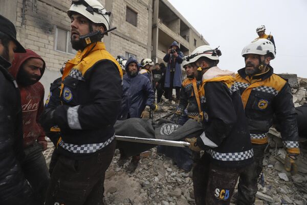 Члены сирийской гражданской обороны, известные как &quot;Белые каски&quot;, перевозят пострадавшего, извлеченного из-под завалов после землетрясения в городе Зардана в Идлибе. - Sputnik Южная Осетия