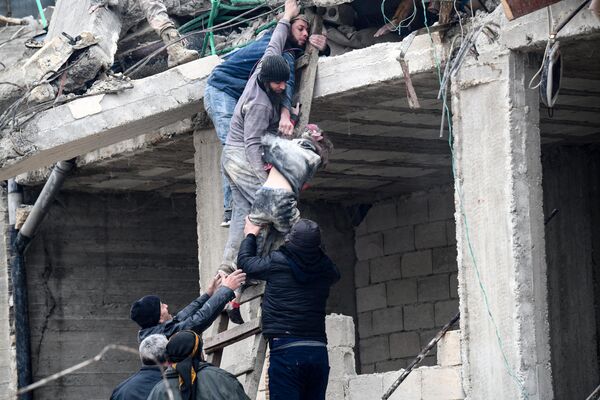 Жители извлекают раненую девочку из-под обломков разрушенного здания после землетрясения в городе Джандарис в сельской местности города Африн на северо-западе Сирии. - Sputnik Южная Осетия