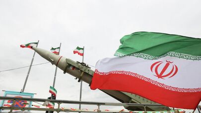 Иранский флаг рядом с ракетой, выставленной на всеобщее обозрение во время празднования 47-й годовщины Исламской революции в Тегеране