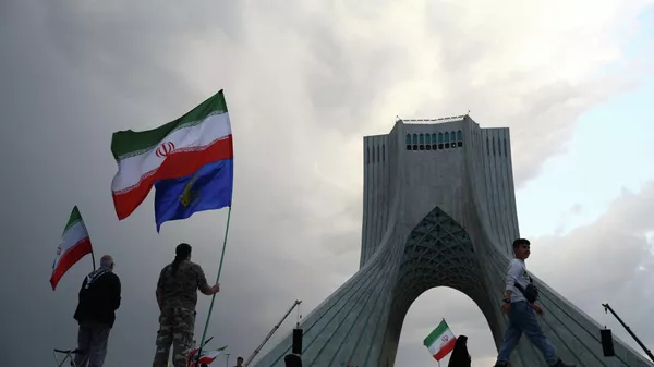 Люди держат иранские флаги во время митинга в Тегеране. Архивное фото  - Sputnik Южная Осетия
